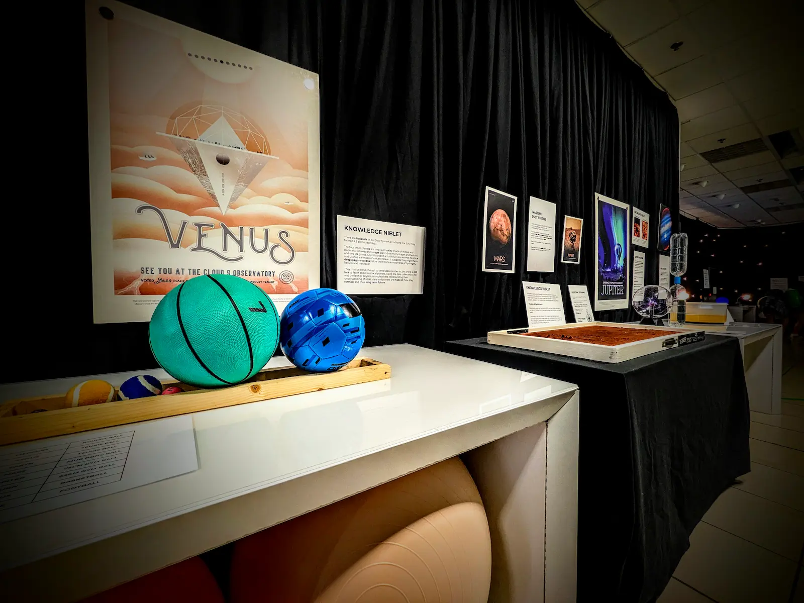 Interactive Venus educational exhibit featuring labeled terrain maps, planet models, and 'Plant Seeds of Change' sign.
